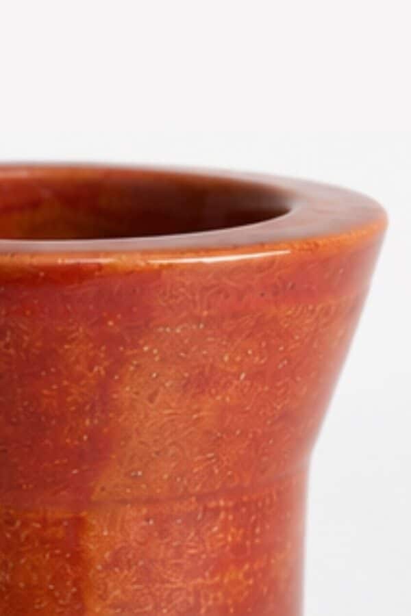Detalle del borde redondeado y el esmalte rojizo de un mate de cerámica terracota